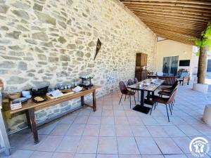 un patio con mesa, sillas y pared de piedra. en Le Coq du Nord - Mailhac Gîte et Chambres d'Hôtes, en Mailhac