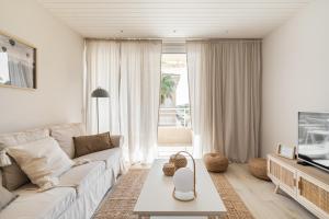 ein Wohnzimmer mit einem weißen Sofa und einem TV in der Unterkunft Alma Home Vendrell Playa in Calafell