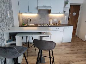 a kitchen with white cabinets and two chairs and a sink at Apartman Emy in Karlovac +6 photos