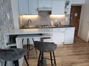 a kitchen with white cabinets and a sink and two chairs at Apartman Emy in Karlovac