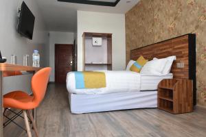 um quarto com uma cama, uma secretária e uma televisão em Centric Hotel em Kigali