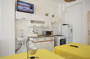 a kitchen with white cabinets and a yellow table with a sink at Centrál Panzió in Szentes