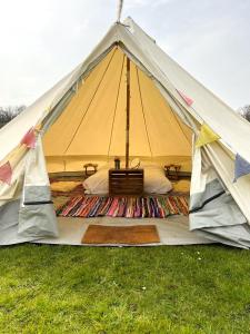 a yellow tent with a bed in the grass at Strawberry Fields Glamping at Cottrell Family Farm in Wokingham