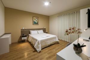 um quarto com uma grande cama branca e uma mesa em Hotel Itapema em Valinhos