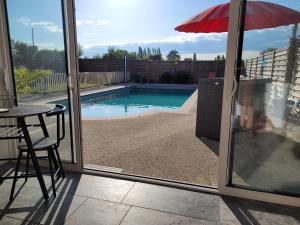 uma vista para uma piscina através de uma porta de vidro deslizante em La pool house em Saint-Aubin-du-Plain