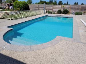 einen Pool mit blauem Wasser im Hof in der Unterkunft La pool house in Saint-Aubin-du-Plain