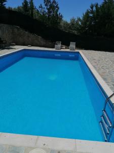 una gran piscina azul con 2 sillas. en Charming House with Pool & Barbecue, en Valle de Abdalajís