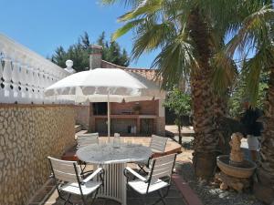 un patio con una mesa, sillas y una palmera en Charming House with Pool & Barbecue, en Valle de Abdalajís