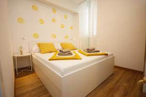 a bedroom with a large white bed with yellow accents at Apartment Passage Dubrovnik in Dubrovnik