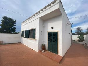 - un bâtiment blanc avec des portes vertes et une cour dans l'établissement Villa Alma, à Collepasso