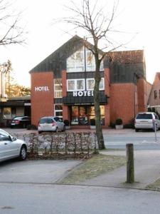 a hotel with cars parked in front of a building at Einfelder Hof garni in Neumünster
