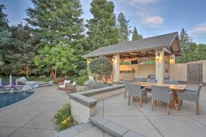 a patio with a table and chairs next to a pool at Redding Getaway with Hot Tub and Outdoor Kitchen! in Redding