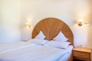 a bed with a large wooden headboard and two pillows at Ferienparadies Sabina Joch in Alpe di Siusi