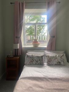 a bed with two pillows in a bedroom with a window at 29 The Square in Listowel