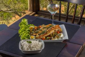 a plate of food with rice and a glass of wine at Recanto Apoena in Santa Isabel