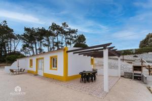 uma pequena casa amarela e branca com uma mesa em Casas de Campo - Real Mar na Ericeira
