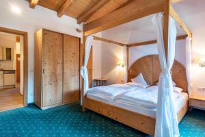a bedroom with a wooden bed with a canopy at Ferienparadies Sabina Föhre in Alpe di Siusi