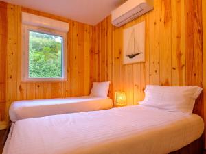 Résidence Les Suites Du Ferret في كاب فيريه: سريرين في غرفة بجدران خشبية ونافذة