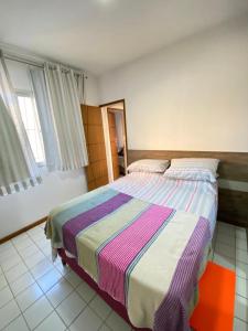 a bedroom with a bed with a colorful striped blanket at Apt temporada guarapari in Guarapari