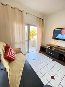 sala de estar con sofá y TV de pantalla plana en Apt temporada guarapari en Guarapari