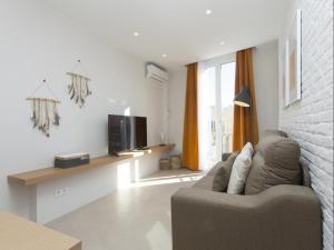 a living room with a couch and a tv at Sunny Playa Apartment in Barcelona