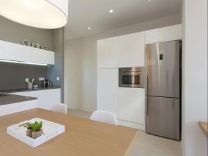 Sunny Playa Apartment في برشلونة: مطبخ مع طاولة خشبية وثلاجة