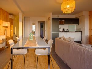 a dining room and living room with a table and a couch at Résidence Les Suites Du Ferret in Cap-Ferret
