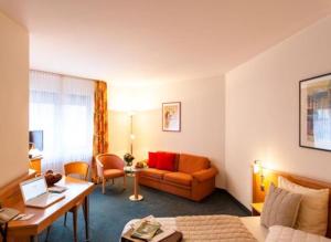 ein Hotelzimmer mit einem Sofa und einem Schreibtisch in der Unterkunft Hotel Panorama Hamburg-Harburg in Hamburg