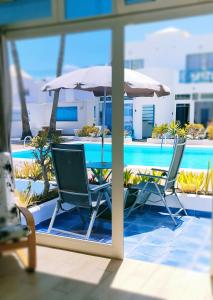 two chairs and an umbrella next to a swimming pool at BLU in Puerto del Carmen