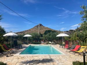 a swimming pool with chairs and umbrellas and a mountain at Casa degli Ulivi 21 in Castellammare del Golfo