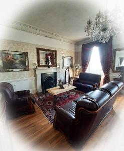 a living room with leather furniture and a fireplace at Highlander House B&B in Rothesay