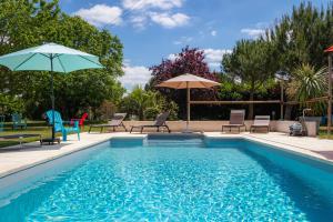 basen z leżakami i parasolami obok niego w obiekcie Gite 4 personnes avec piscine entre Saintes et Royan w mieście Balanzac