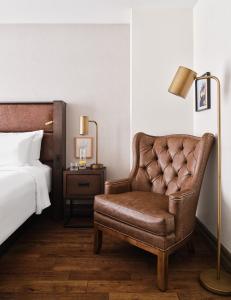 a bedroom with a bed and a brown leather chair at The Metcalfe by Gray Collection in Ottawa