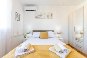 ein Schlafzimmer mit einem weißen Bett und Handtüchern darauf in der Unterkunft Apartments Plokite in Split