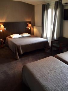 ヴァランスにあるHotel Les Negociantsのベッド2台と窓が備わるホテルルームです。