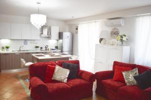een woonkamer met 2 rode stoelen en een keuken bij La Rondine Holidays in Anguillara Sabazia
