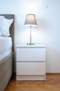 ein weißer Nachttisch mit einer Lampe neben einem Bett in der Unterkunft Apartments Plokite in Split