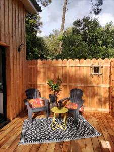 2 chaises et une table sur une terrasse en bois dans l'établissement Lodge 2 étoiles la tête dans les pins les pieds dans l eau, à Lacanau