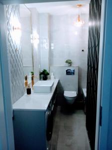 a bathroom with a white sink and a toilet at Apartament z widokiem Łańcut in Łańcut