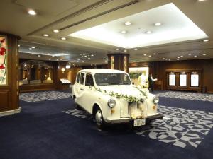 Un coche blanco aparcado en una habitación con flores. en Hotel Higashinihon Utsunomiya en Utsunomiya