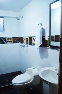 a white bathroom with a toilet and a sink at Qolmay Hostel Cusco in Cusco