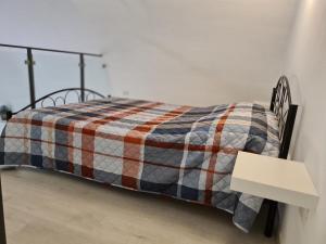 a bed with a checkered blanket and a table at La Giara House in Corato