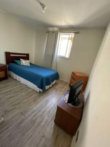 een slaapkamer met een bed en een bureau met een laptop bij Hostal Nomade in Constitución