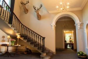 um corredor com uma escada com cabeças de veado na parede em Chirnside Hall Hotel em Chirnside