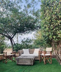 une terrasse avec 2 chaises, un canapé en osier et des tables dans l'établissement Seaside "Stone & Light Villa II" close to Aegina City, à Khlóï