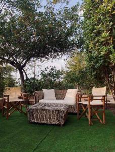 a wicker sofa and chairs sitting on a lawn at Seaside "Stone & Light Villa II" close to Aegina City in Khlóï