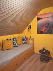Cama en habitación con pared amarilla en Nárcisz Vendégház 2, en Mezőkövesd