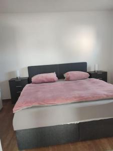 Una cama con dos almohadas rosas encima. en Ferienwohnung Haus Merle, en Jestädt
