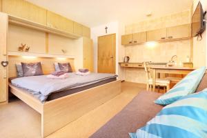 ein kleines Schlafzimmer mit einem Bett und einer Küche in der Unterkunft Appartements Zum Arber in Bayerisch Eisenstein