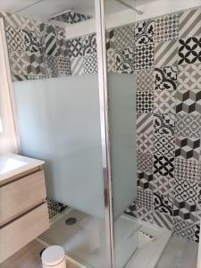 La salle de bains est pourvue d'une douche et de carrelage noir et blanc. dans l'établissement Lodge 2 étoiles la tête dans les pins les pieds dans l eau, à Lacanau